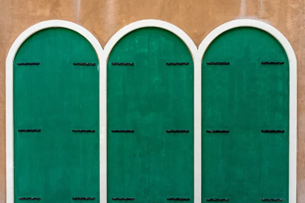 Três portas de madeira verde na parede de concreto marrom — Fotografia de Stock