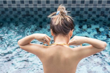 Asyalı kadın özel havuzda bikini üst bağlama