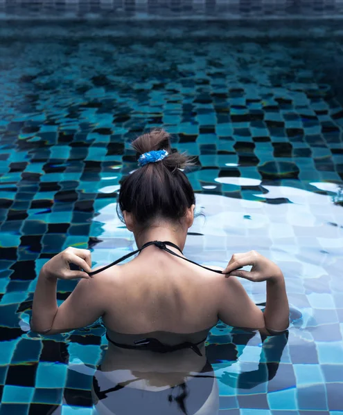 Asyalı kadın siyah bikini üst yüzme havuzunda bağlama