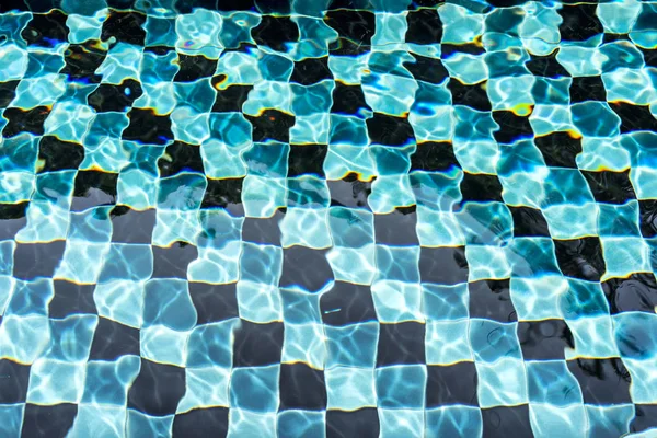 Suelo de mosaico negro y azul de la piscina a la luz del día — Foto de Stock