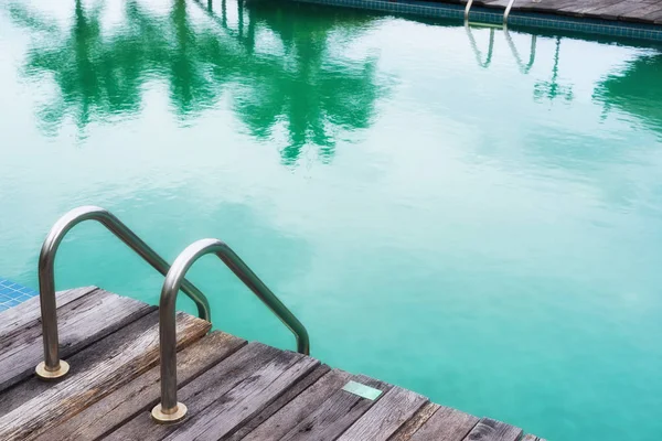 Tom grön pool med stål stege och trägolv — Stockfoto