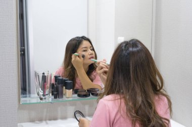 Asyalı kadın ayna yanağına allık fırçası uygulamak