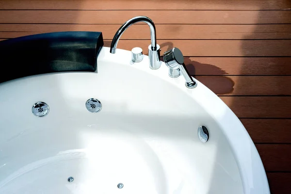 Empty white whirlpool bathtub with faucet on wooden floor — Stock Photo, Image