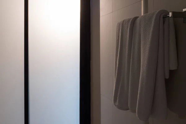 白色毛巾挂在浴室衣架与背光玻璃门 — 图库照片
