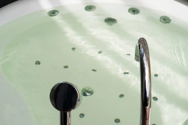 Beyaz Jakuzi küvet su ve çelik duş başlığı ile — Stok fotoğraf