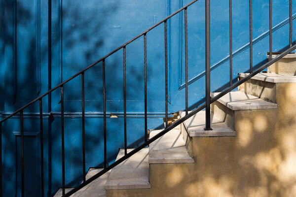 Trees shadow on old yellow stairs and blue wooden wall.
