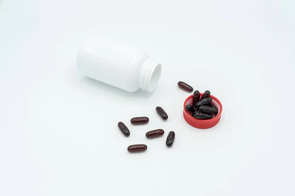 Cápsulas negras, frasco blanco y tapón rojo — Foto de Stock