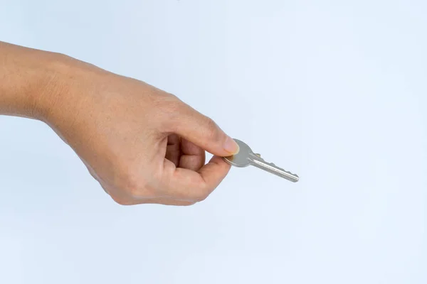 La mano femenina sostiene la llave de metal con el pulgar y el dedo índice — Foto de Stock