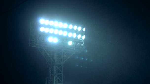 Foco de cremalheira de luzes de estádio na frente de um céu azul escuro . — Vídeo de Stock