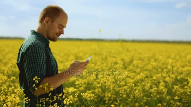 Молодой человек разговаривает по мобильному телефону в поле — стоковое видео
