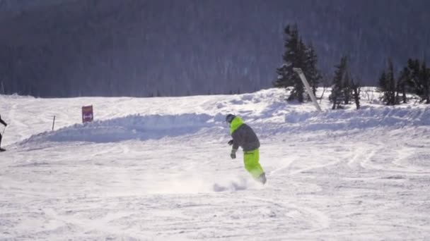 SLOW MOTION CLOSE UP: Snowboarder riding and jumping on ski slope in snowy mountains — Stock Video