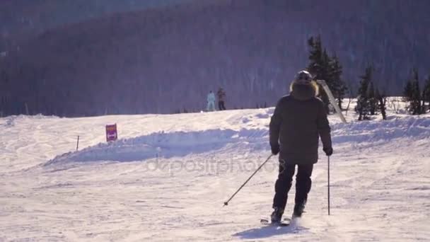 Vista trasera de 4k del esquiador profesional tallando por la ladera nevada — Vídeos de Stock