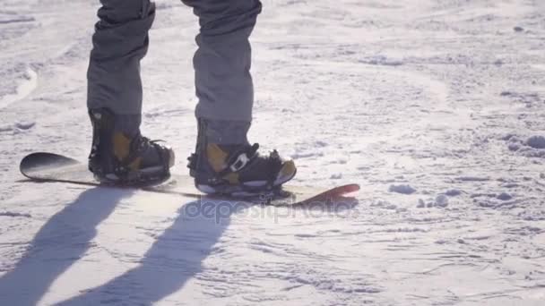 Slow Motion close-up: Snowboarder paardrijden en springen op de skipiste in besneeuwde bergen — Stockvideo