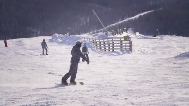 Lento movimiento CERRAR: Snowboarder montar y saltar en la pista de esquí en las montañas nevadas — Vídeos de Stock