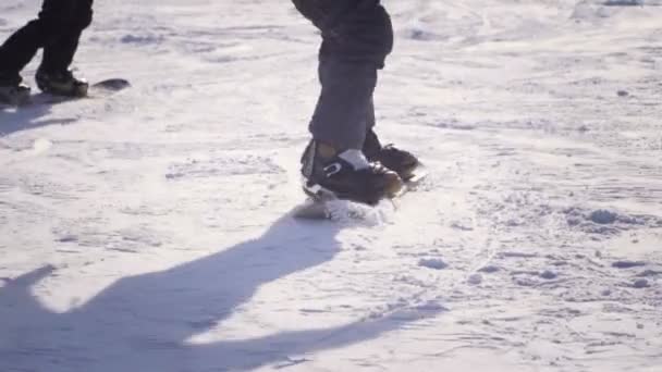SLOW MOTION CHIUSURA: Snowboarder in sella e saltando sulla pista da sci in montagna innevata — Video Stock