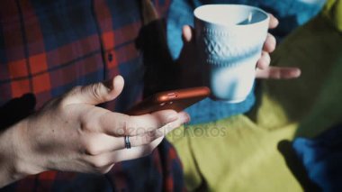 Genç bir kadın bir kafe ve metinler oturur onu cep telefonundan bir fincan kahve yudumlarken