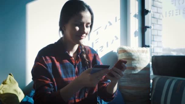 Leende ung kvinna sitter vid bord med touchpad och hålla kreditkort i handen — Stockvideo