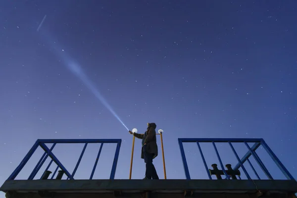 Silhuett av en mann med en lommelykt, som observerer en vakker, bred blå nattehimmel med stjerner og synlig Melkevei-galakse. Astronomi, orientering, klar himmel-konsept og bakgrunn . stockbilde