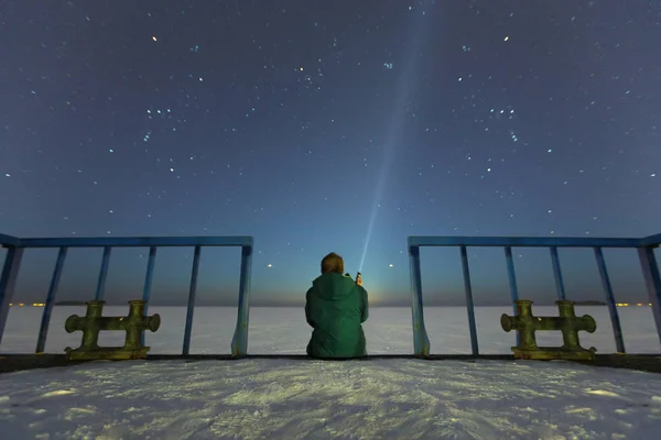Silhuetten av en man med en ficklampa, observerar vackra, breda blå natthimmel med stjärnor och synliga Vintergatan. Astronomi, orientering, klar himmel koncept och bakgrund. Stockbild