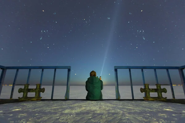 Silhouette of a man with a flashlight, observing beautiful, wide blue night sky with stars and visible Milky way galaxy. Astronomy, orientation, clear sky concept and background. Stock Picture