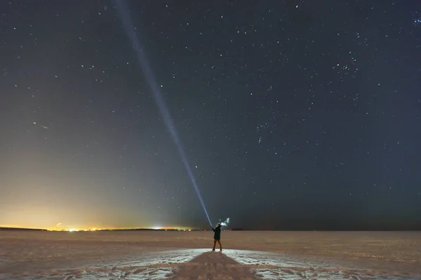 Silhuetten av en man med en ficklampa, observerar vackra, breda blå natthimmel med stjärnor och synliga Vintergatan. Astronomi, orientering, klar himmel koncept och bakgrund. Royaltyfria Stockbilder