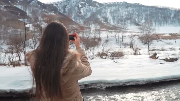 Hermosa mujer caucásica tomando selfie contra el fondo de grandes montañas y río de montaña verde — Vídeos de Stock