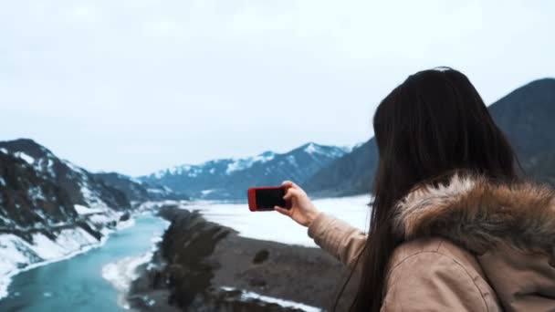 Bella donna caucasica scattare selfie sullo sfondo di grandi montagne e verde fiume di montagna — Video Stock