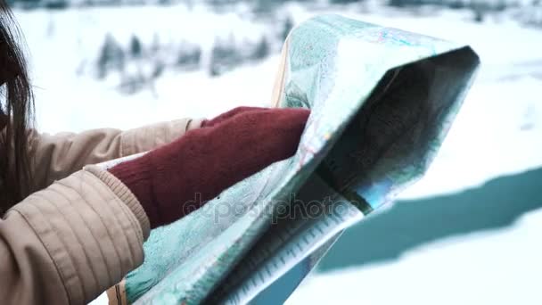 Joven turista explorando el mapa de montaña mientras viaja en las montañas en invierno, concepto de vacaciones — Vídeos de Stock