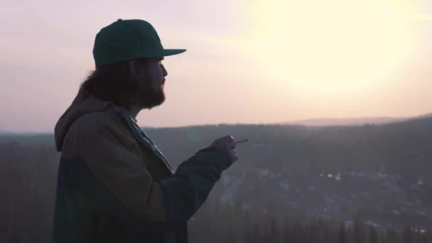 Porträtt av en ensam man, röka en cigarett vid solnedgången. En man röker en cigarett. — Stockvideo