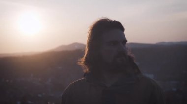 Gün batımında genç bir adam portresi. Uzun kıvırcık saç