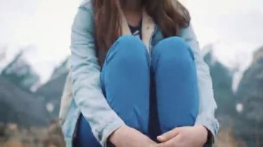 Genç kız Gezgin dağlar, kameraya gülümseyen manzarayı kayanın üzerinde oturur