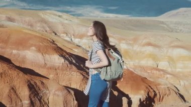 Mutlu esmer kız gülümseyerek, kameraya seyir sırt çantası ile. Kırmızı Dağları kar ile bir arka plan üzerinde.