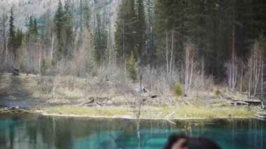 Mutlu kız Gezgin kayanın üzerinde oturur, bir dağ krater Gölü görünüyor. Bir kot ceket yürüyüş ve sırt çantası hiking giyinmiş. Yalnız, kendinizi bulma seyahat