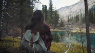 Mutlu kız Gezgin kayanın üzerinde oturur, smartphone Dağı krater Gölü üzerinde bir resim yapar. Bir kot ceket yürüyüş ve sırt çantası hiking giyinmiş. Yalnız, kendinizi bulma seyahat.