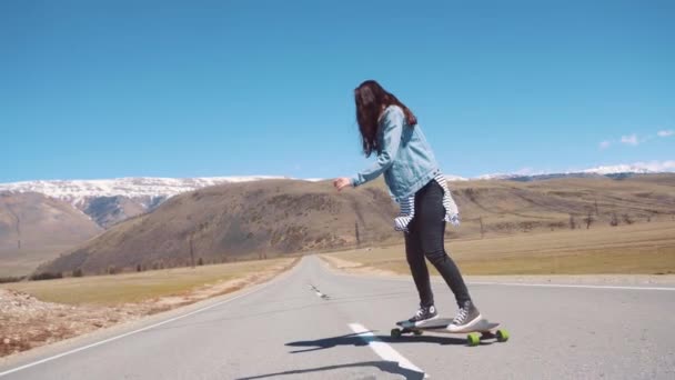 俄罗斯 kuray-01.05.2017： 女子滑板在路上飞驰。女人做退潮下坡，骑得快。在青年或孤独的自由的感觉. — 图库视频影像