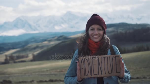 Tienermeisje houden een avontuur-teken op een bergweg, glimlacht en lacht — Stockvideo