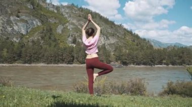 Genç güzel kadın kırmızı tank top açık havada, pratik bükme ağaç duruş, Vrksasana, Park yaz gününde varyasyonu yapıyor. Altay, nehir katun.