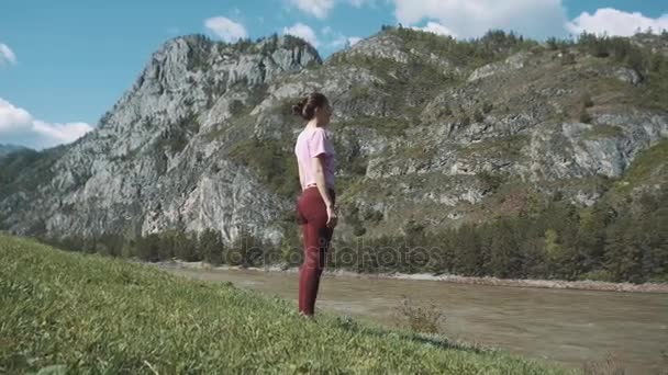 Jonge mooie vrouw in rode tank top beoefenen buitenshuis, doen buigen boom houding, variatie van Vrksasana, in park op zomerdag. Altaj, de rivier katun. — Stockvideo