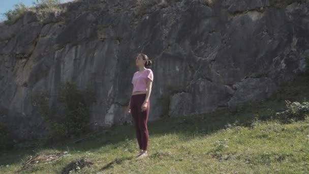 Молодая красивая женщина в красной майке практикуется на открытом воздухе, делает позу согнутого дерева, вариации Vrksasana, в парке в летний день. Алтай, река Катун . — стоковое видео