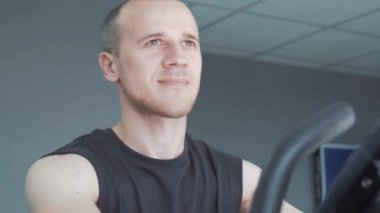 Genç çekici adam spor salonunda egzersiz bisikleti Bisiklete binme