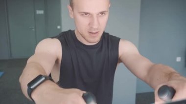 Spor salonunda sabit bisiklet sürme smartwatch ile genç adam