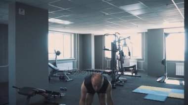 Halter salonunda - kas eğitim. Adam spor salonunda halter kaldırıyor. Haddelenmiş koca adam trenler dumbbells ile. Spor salonunda antrenör. Yaşam tarzı.