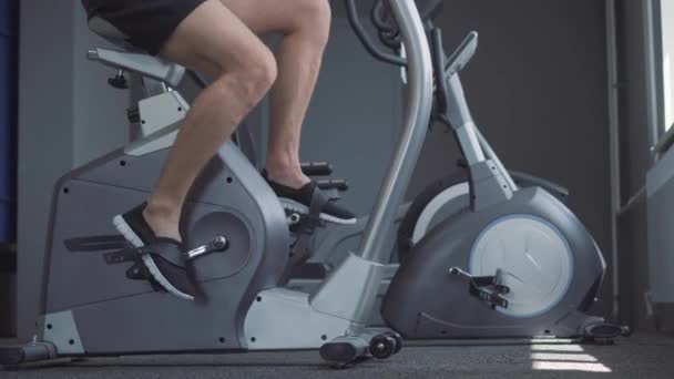 骑自行车在健身房运动的年轻有魅力的男人 — 图库视频影像