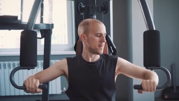 Ung muskulös Man utbildning hårt på roddmaskin i fitnesstudio — Stockvideo