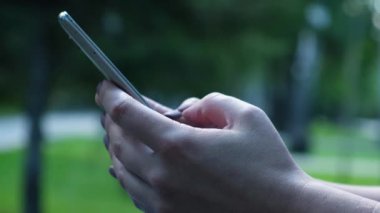 Eller Closeup kullanım dokunmatik ekranındaki bilgileri aracılığıyla Thumbing bir Smartphone. belgili tanımlık telefon perde güneş ışığını yansıtır.