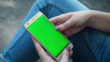 Genç kız Holding Smartphone ile yeşil perde, akşam saat var. Rahat yaşam tarzı.