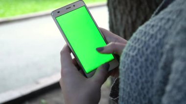Genç kız Holding Smartphone ile yeşil perde, akşam saat var. Rahat yaşam tarzı.