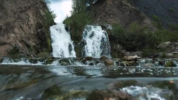 Närbild av ett litet vattenfall i en djup skog. Vackra små turist vattenfall. En liten sjö som faller ett vattenfall — Stockvideo