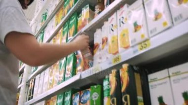 Ufa Rusya - 30.08.2017: Kadın süpermarkette suyu seçer. Alışveriş merkezinde ürünlerini seçtiğiniz bir kadın. Kız mağaza raf standları ve ürünleri seçer