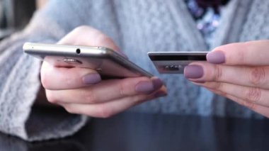 Genç beyaz kadın onun smartphone kendi kredi kartı ile internetten satın alma ürünler eller